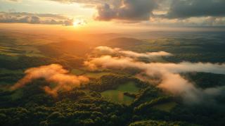 Aerial view of sunset and clouds across a landscape of forests and rivers