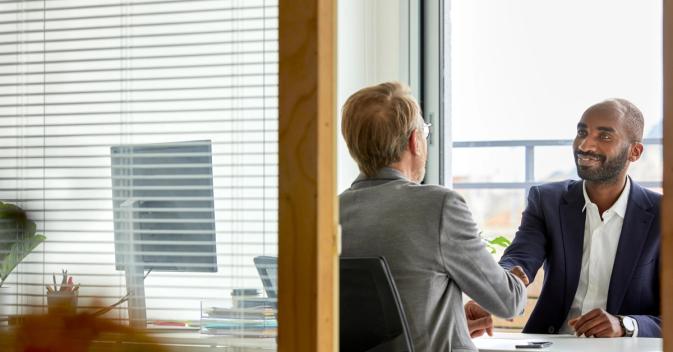 Two people shaking hands in a financial office