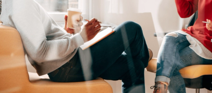 Two people having an office meeting, taking notes on a notebook
